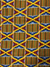 African kente print fabric in bold yellow, blue, red and black in a traditional kente design pattern.
